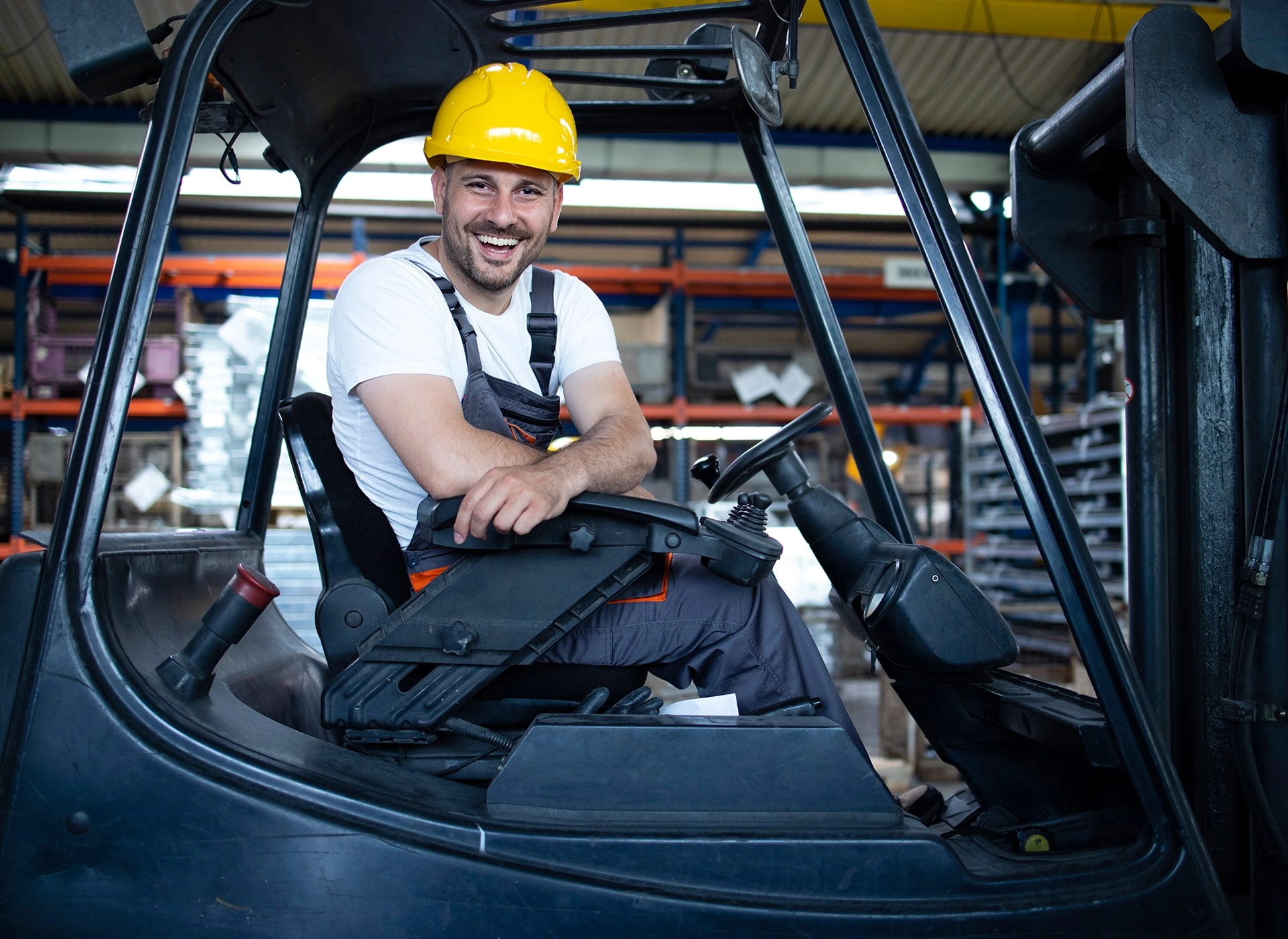 Arbeiter fährt einen Gabelstapler und trägt einen Schutzhelm