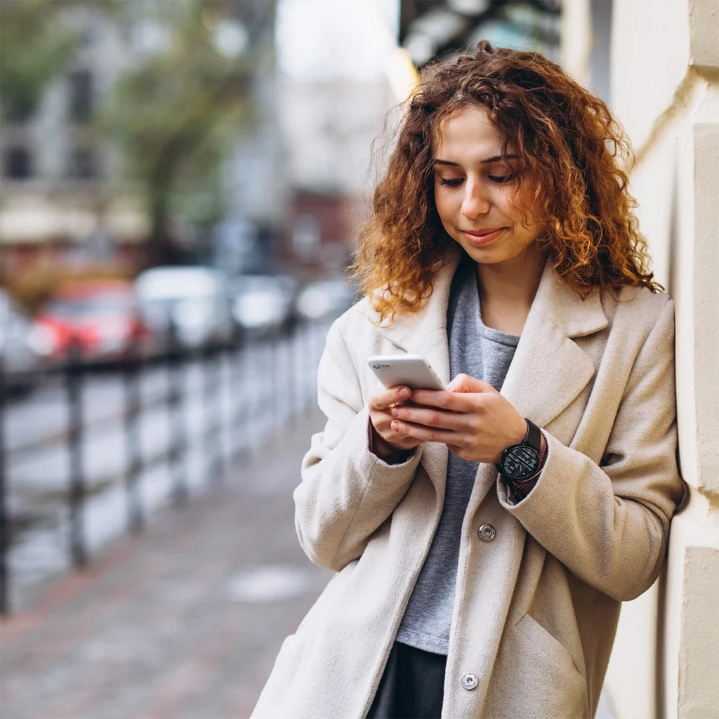 Arbeiterin schreibt eine Nachricht auf ihrem Telefon auf der Straße